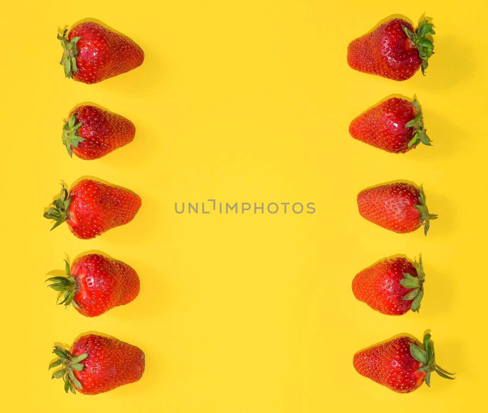 Fresh Strawberries close up. Strawberries isolated on bright yellow background with free space. Frame, template or mock up. Flat lay.