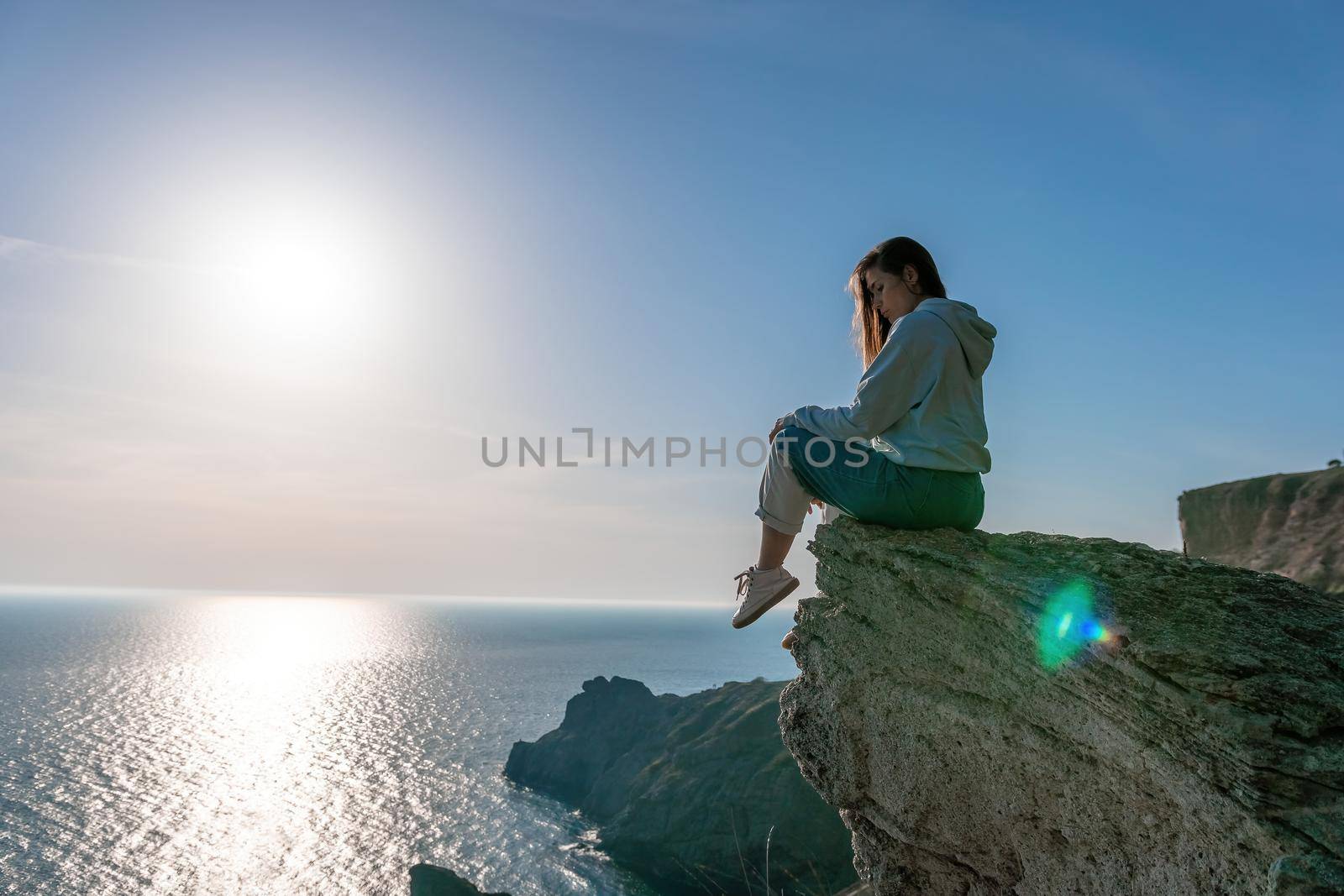 woman traveler drinks coffee with a view of the mountain landscape. A young tourist woman drinks a hot drink from a cup and enjoys the scenery in the mountains. Trekking concept