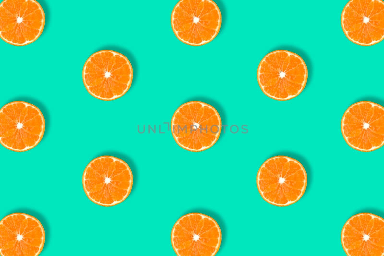 Fruit pattern of fresh mandarin slices isolated on blue or mint background. Flat lay, top view. Pop art design, creative summer concept. Half of tangerine citrus in minimal style.