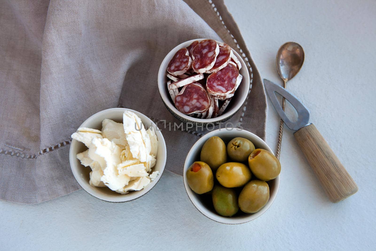 Antipasto catering platter with different meat and cheese products. cheese, olives and ham for a simple breakfast. linen napkin and small knife