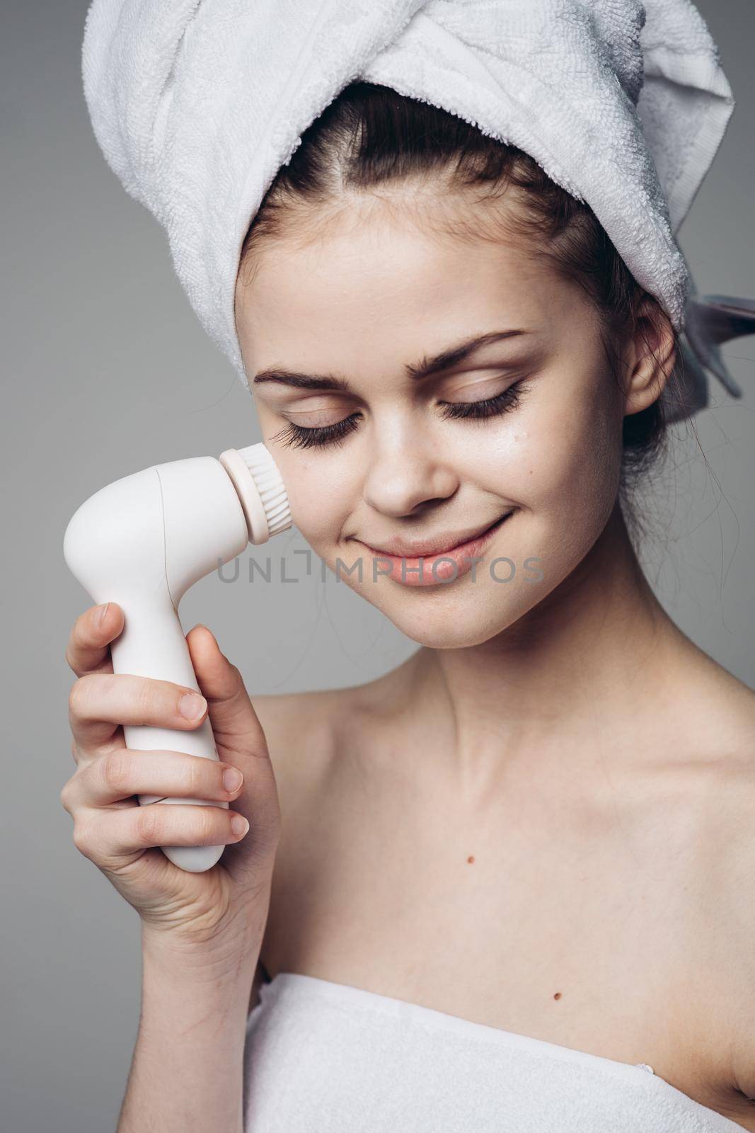 woman with towel on head facial massager skin care hygiene. High quality photo