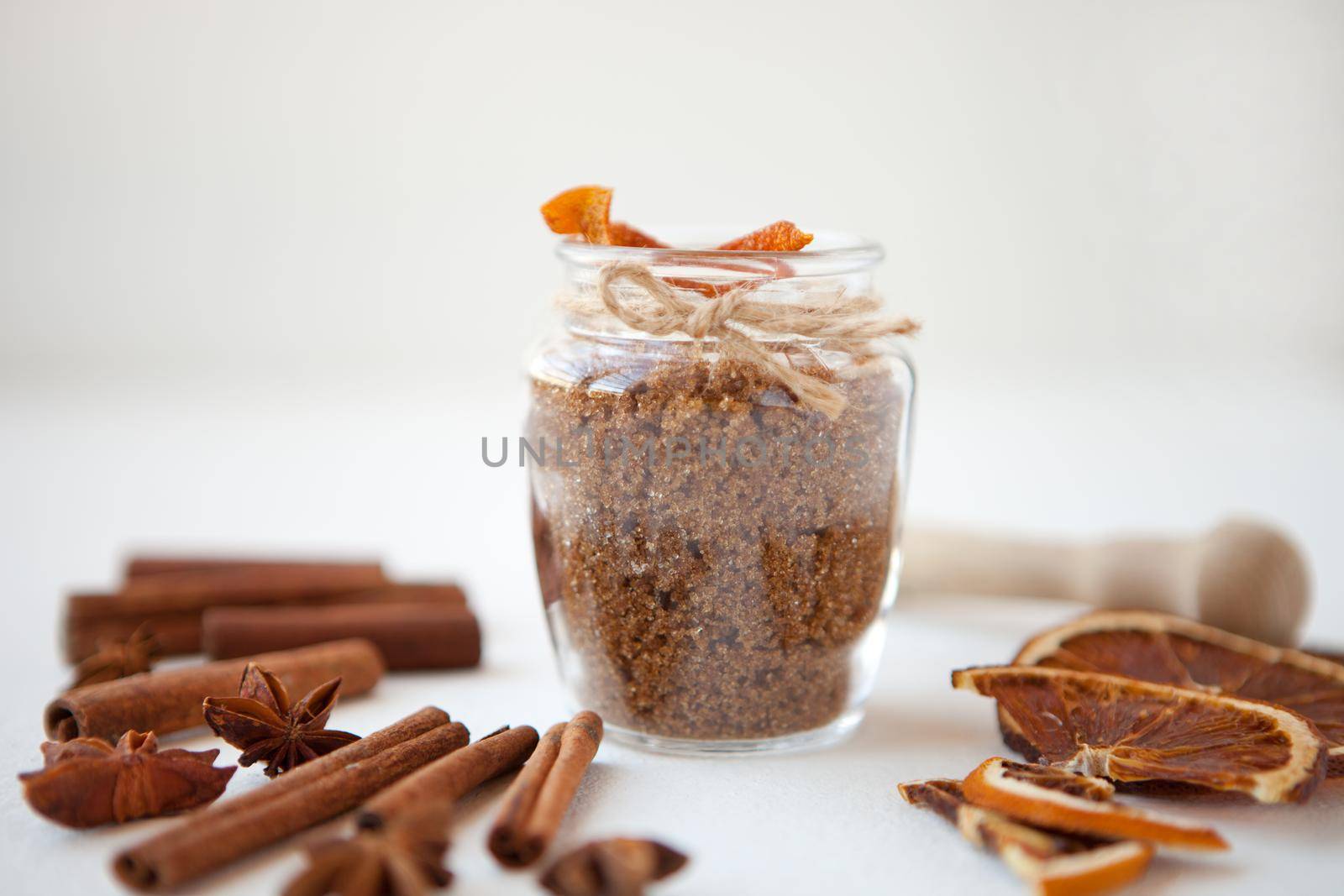 Cinnamon sticks, dried oranges and star anise with brown sugar bottle with shallow depth of field on white background. Baking ingredients for cooking