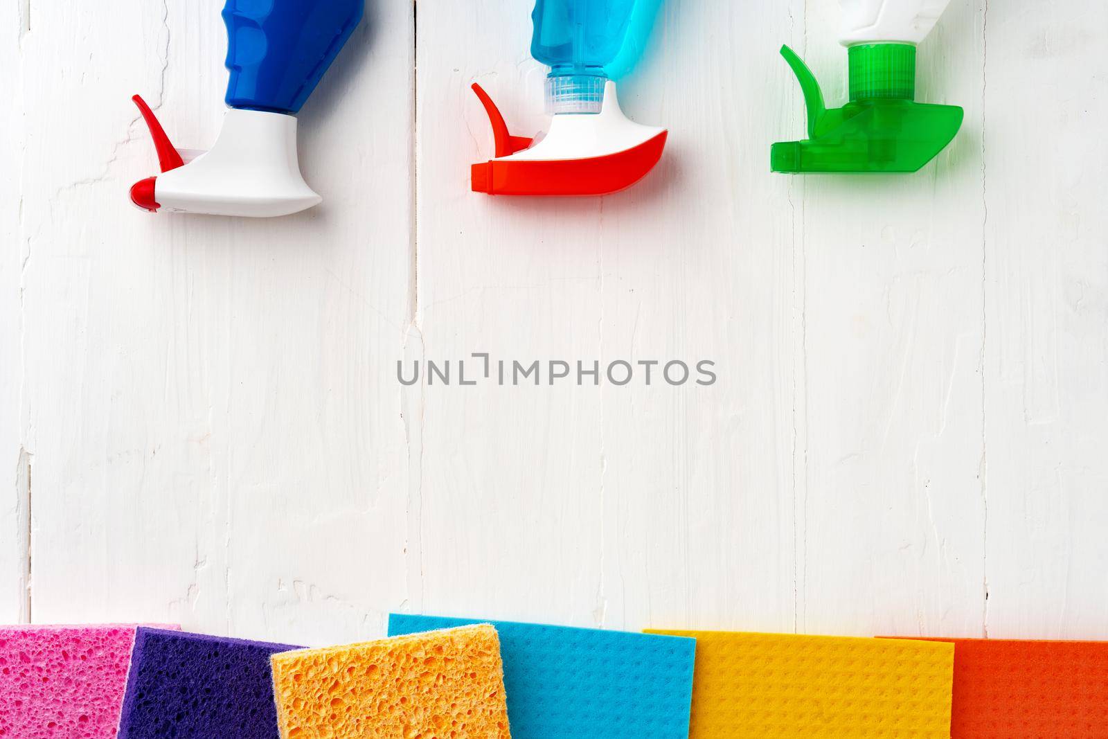 Home cleaning supplies on white wooden background, top view photo