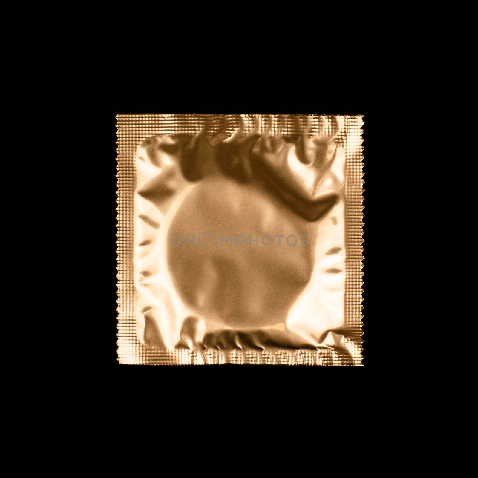 Condom in golden foil packaging isolated on black background. by esvetleishaya