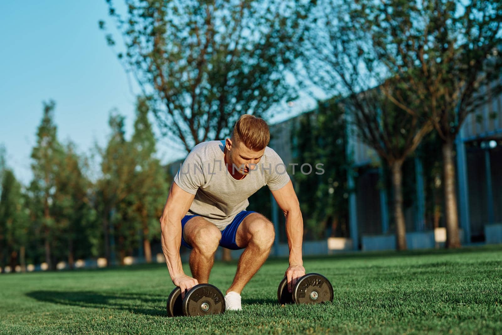 athletic man with dumbbells in the park exercise motivation by Vichizh