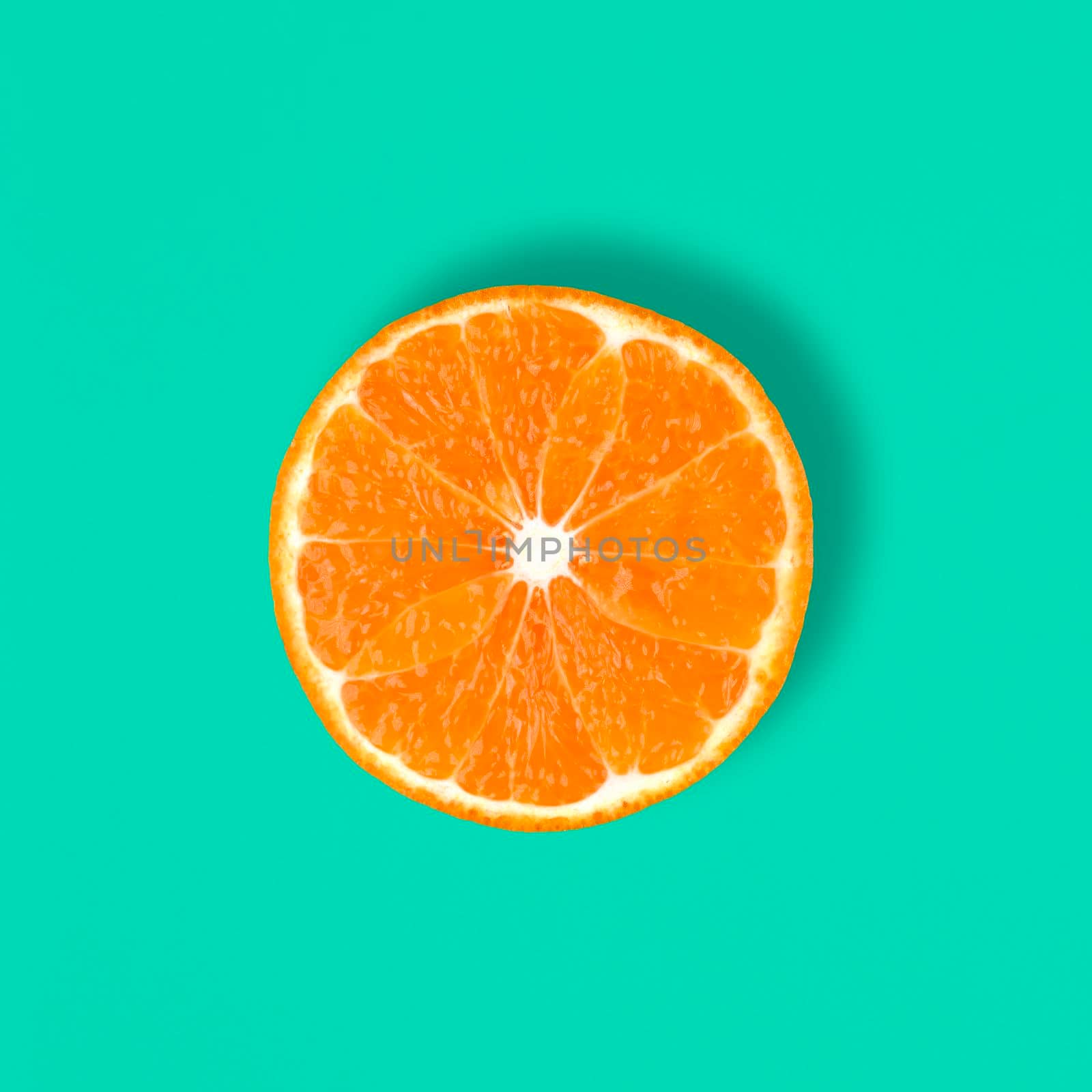 Cut Mandarin fruit isolated on a blue or mint background. Ctrus round slice. Food background. Top view, flat lay..
