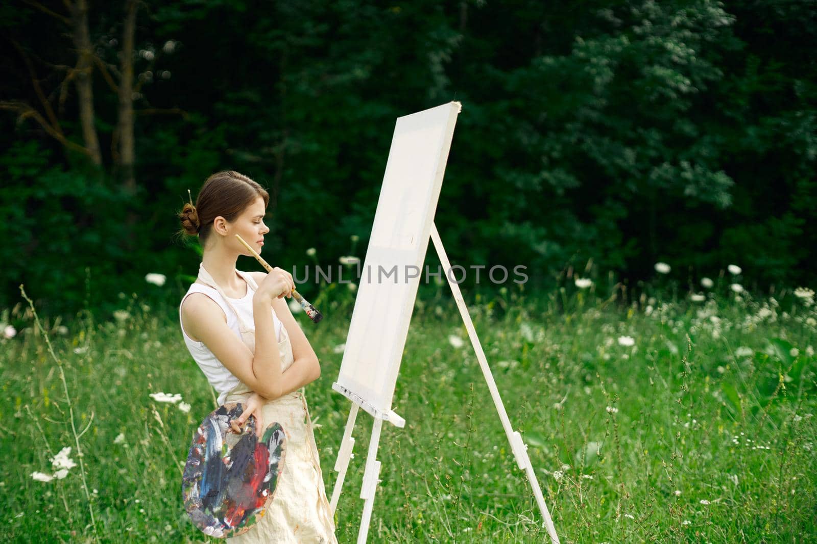 woman artist with palette of paints drawing easel nature hobby by Vichizh
