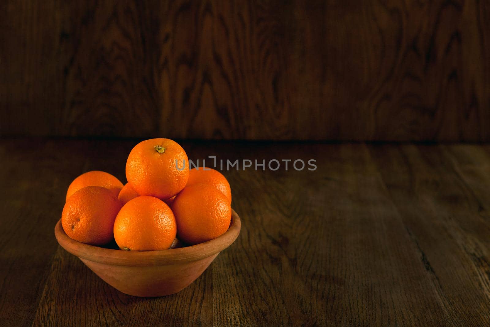 A lot of oranges on the bowl - dark background. Still life fruits in vintage style. Tasty oranges at the bowl dark photo