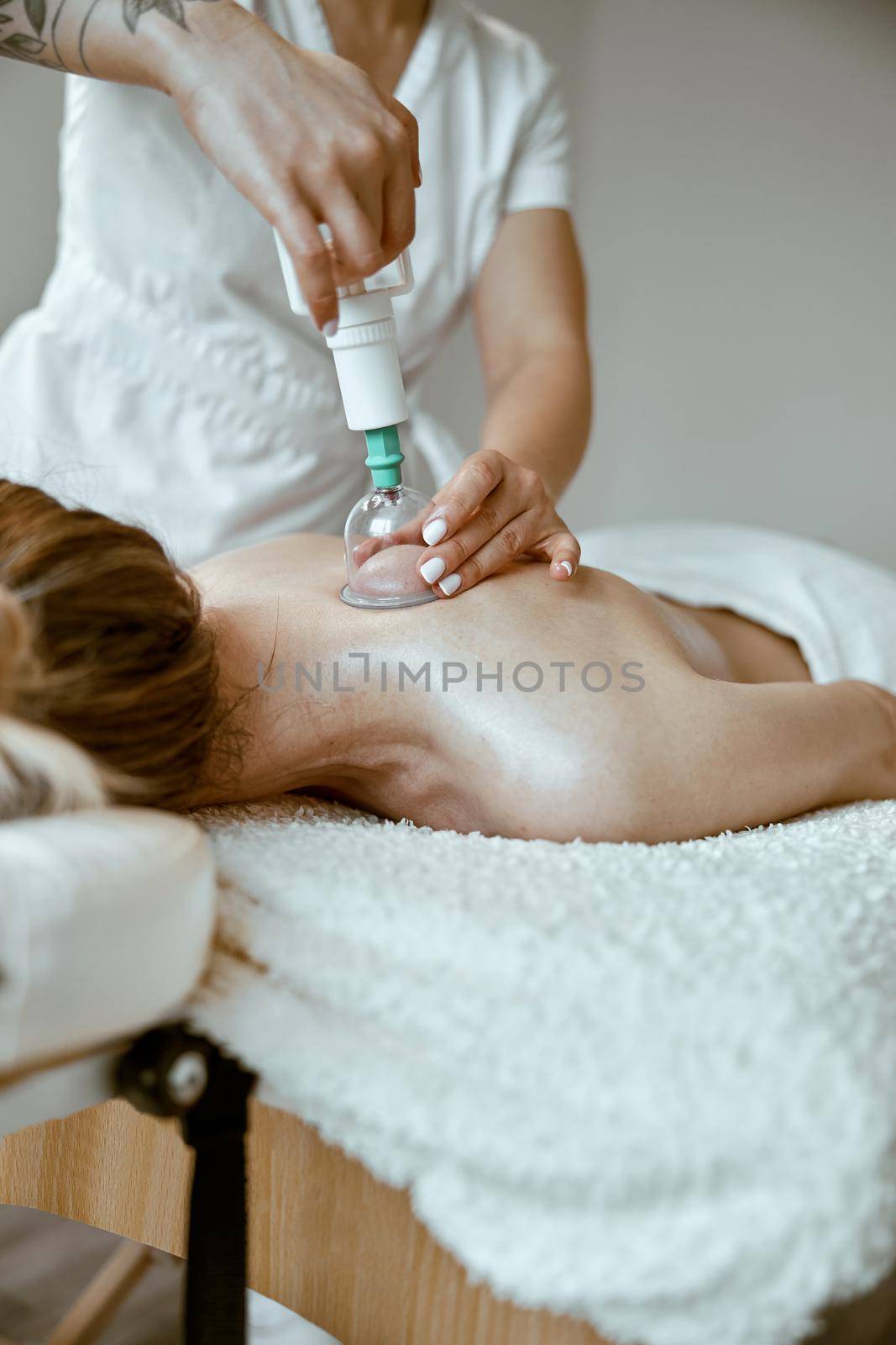 professional female specialist is doing cupping therapy on the back of beautiful caucasian lady