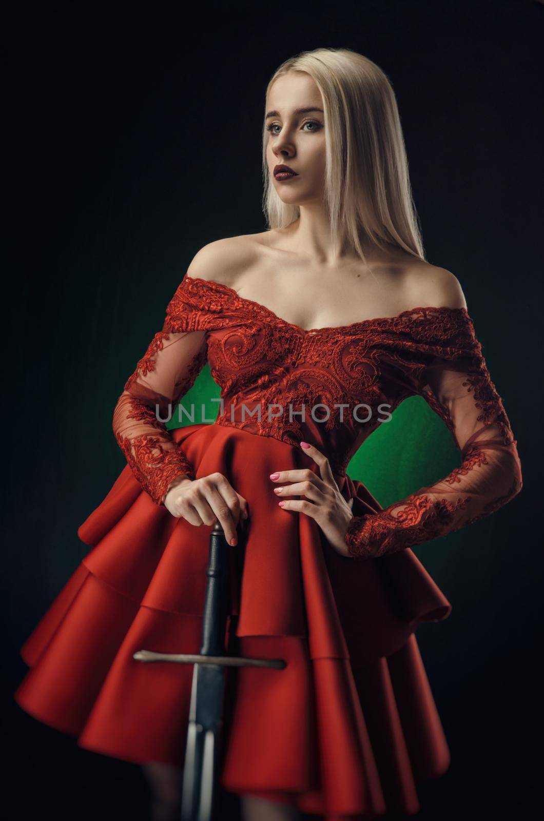 lovely girl in red dress with sword posing on black background in Studio (blonde )