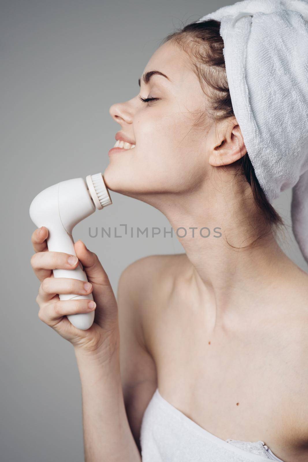 woman with towel on head facial massager skin care hygiene. High quality photo