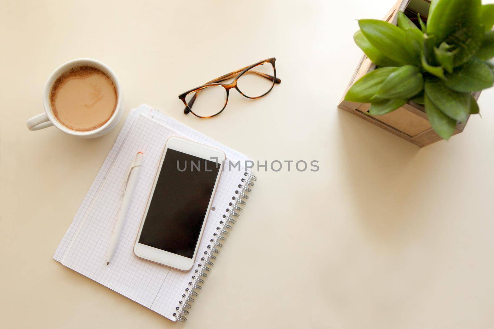 Mobile phone and notes paper. Retro style interior - cozy working place at home stylish interior in warm pastel colors, table and white coffee mug with glasses. stay at home - a place for home office or a place to relax.