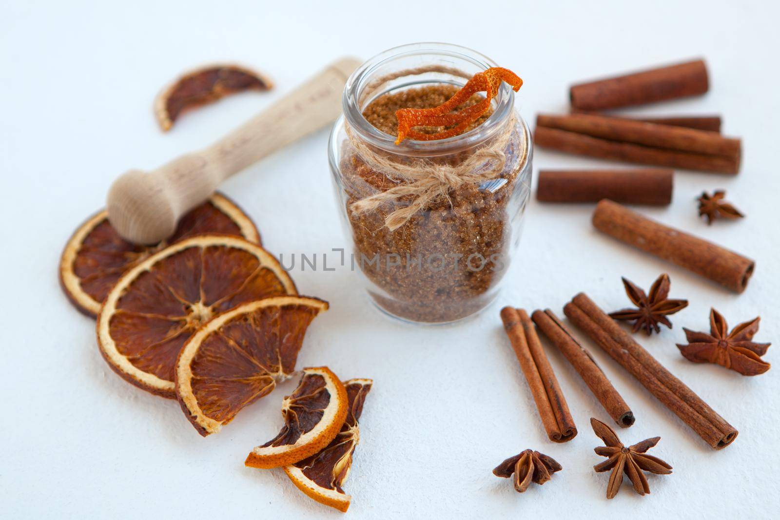 Cinnamon sticks, dried oranges and star anise with brown sugar bottle with shallow depth of field on white background. Baking ingredients for cooking