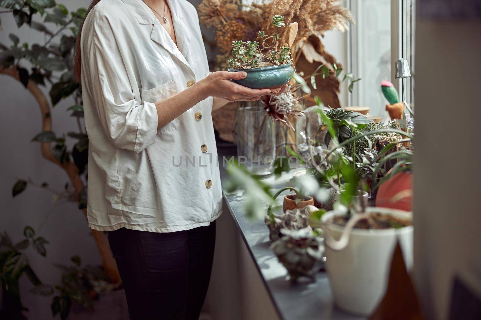 caucasian confident happy florist is working with composition made from glass stones and plants in botanic shop