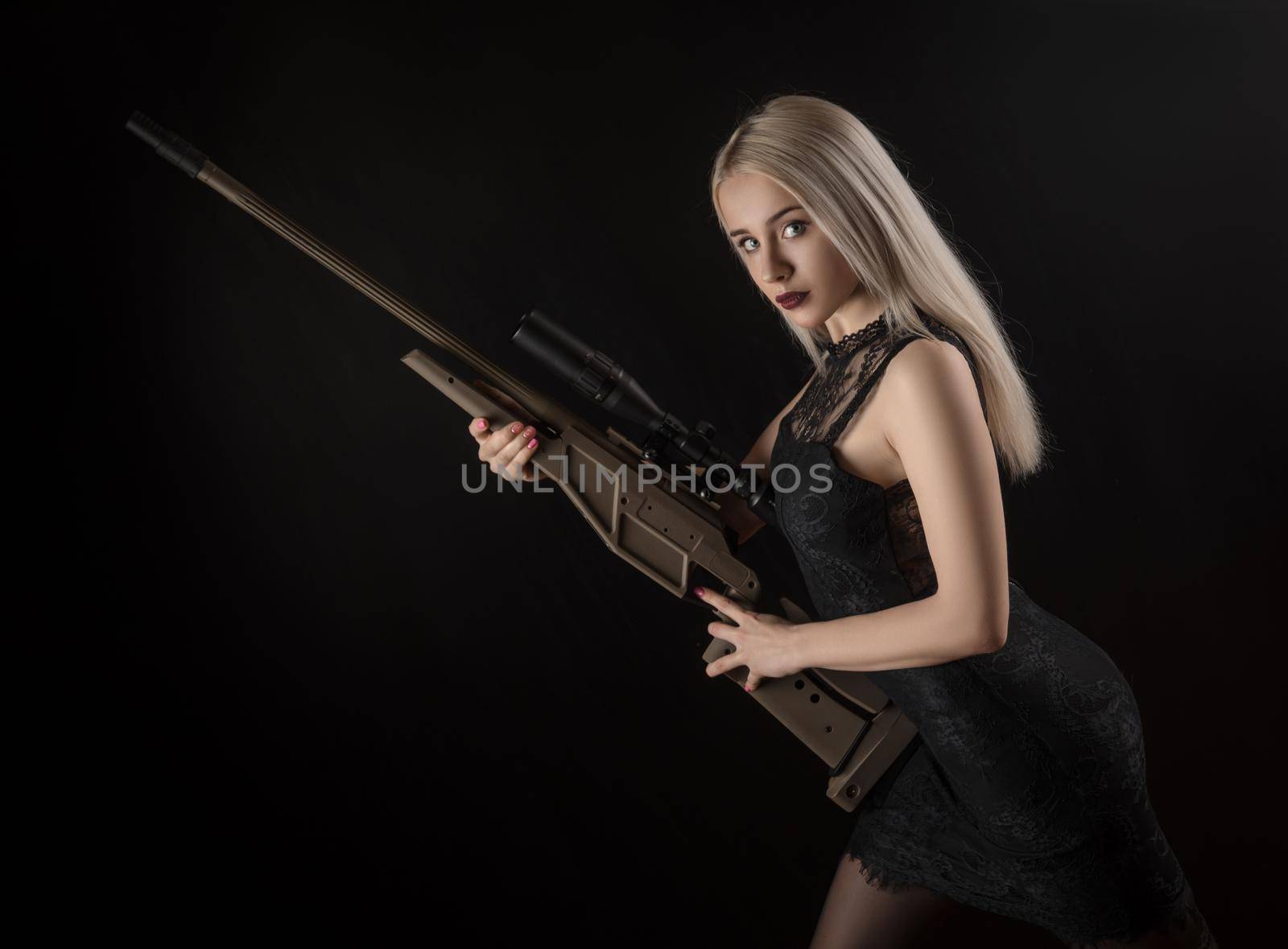 young blonde girl in black dress posing on black background with weapon by Rotozey