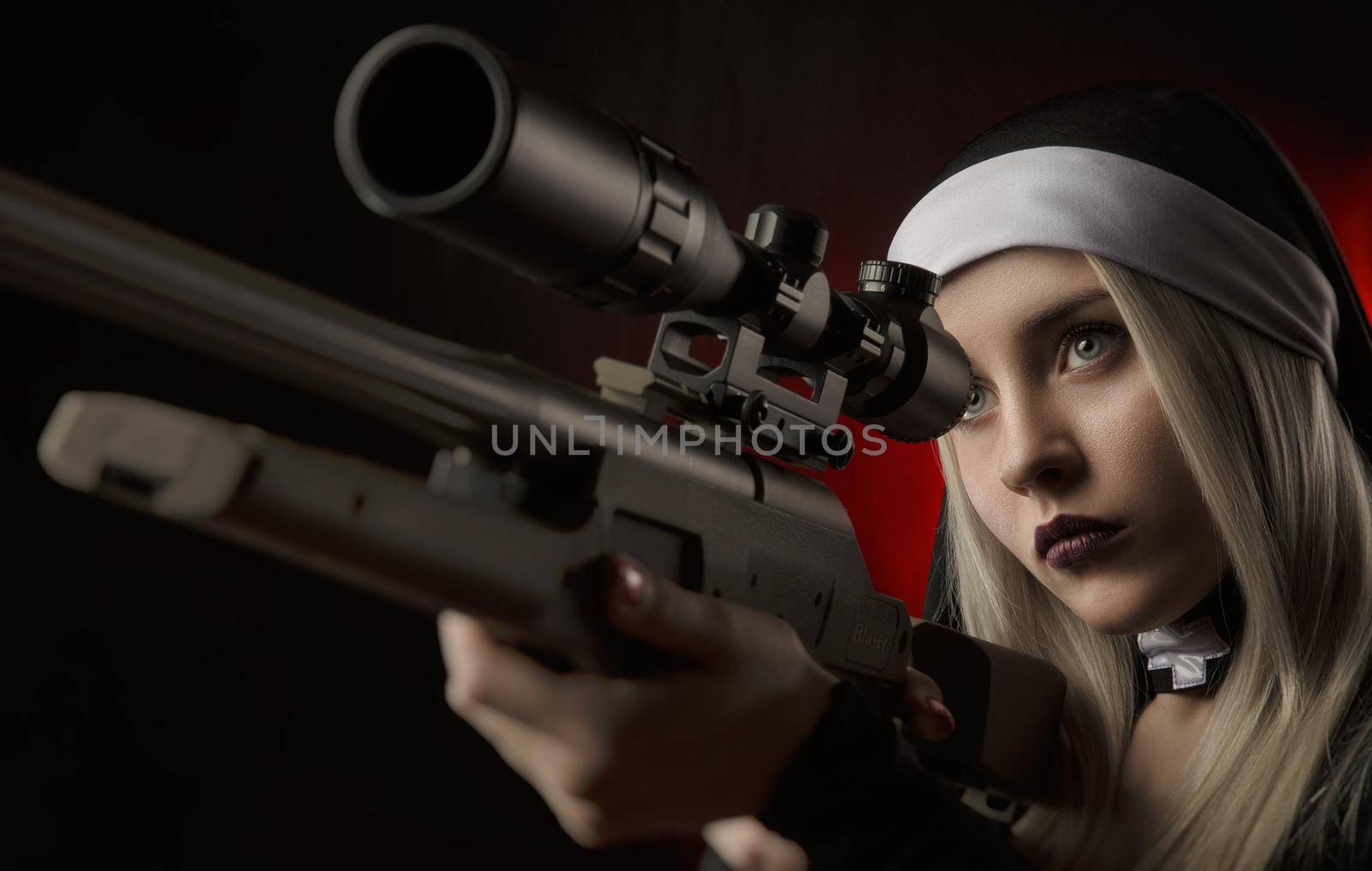 the girl on a black background in a nun dress posing with a gun, aiming, shooting