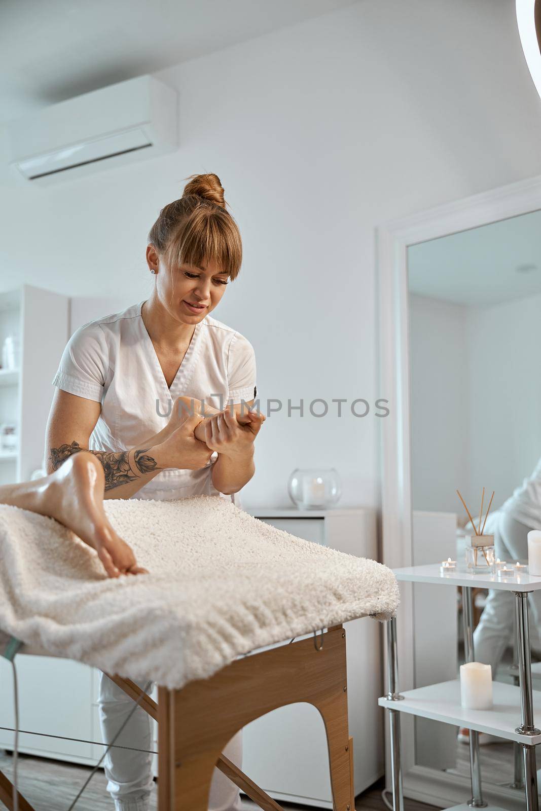 Professional confident massage master is doing procedures to caucasian woman in minimalistic modern cabinet