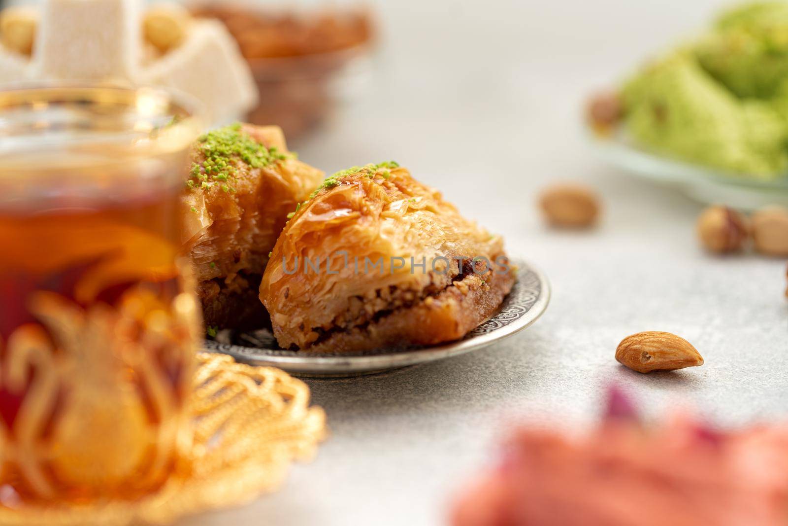 Assortment of Turkish delights with glass of tea on gray background, close up