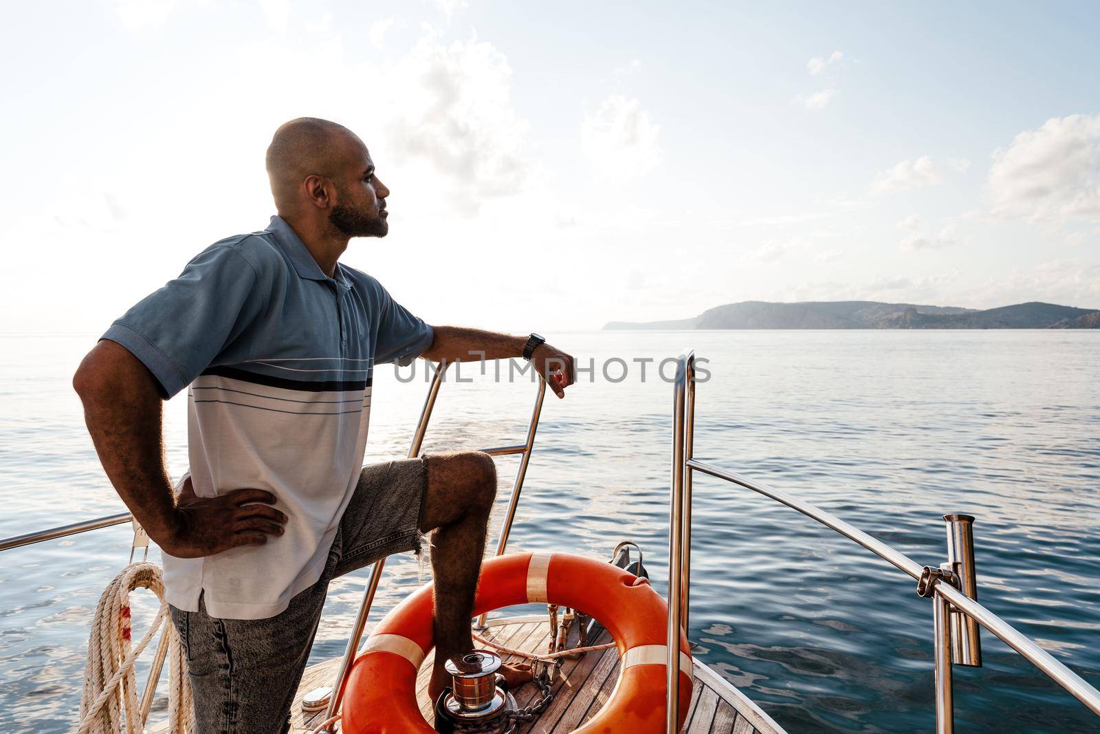 Young african american man relaxing on a sailboat in open sea at sunset, close up