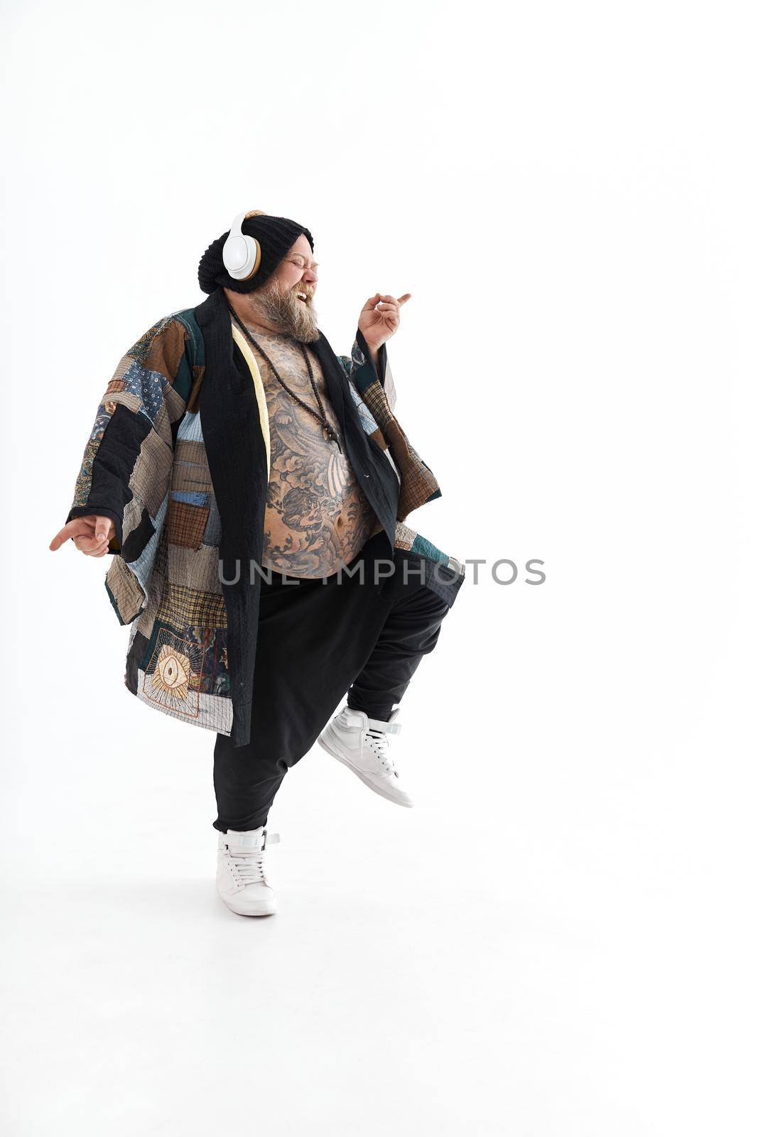 Fat stylish bearded tattoed caucasian man with big belly is posing and dancing wearing ethnic kimono by Yaroslav_astakhov