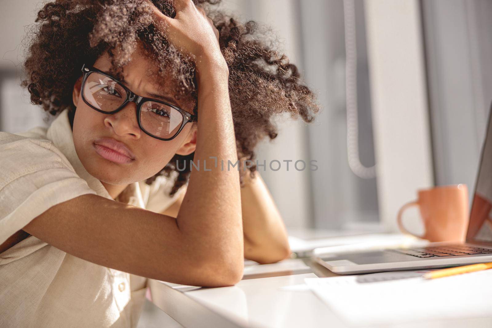 Tired Afro American woman sitting at her desk by Yaroslav_astakhov