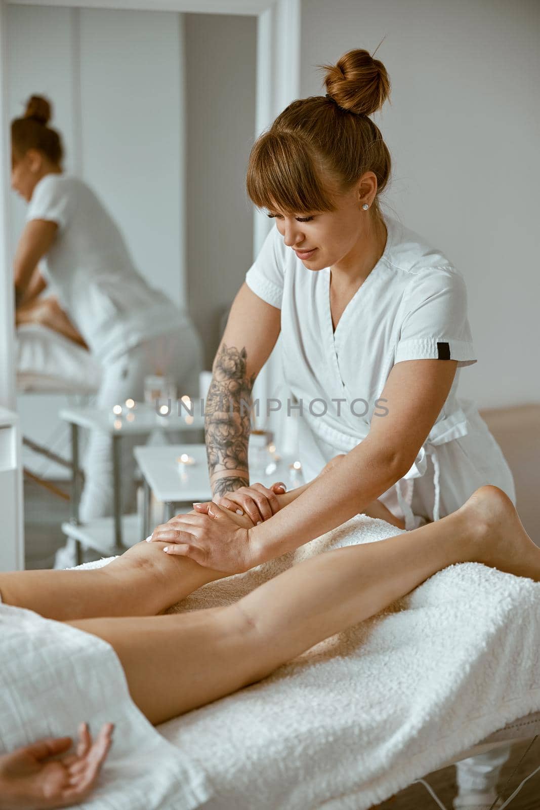 Professional caucasian specialist is doing leg message at modern minimalistic salon