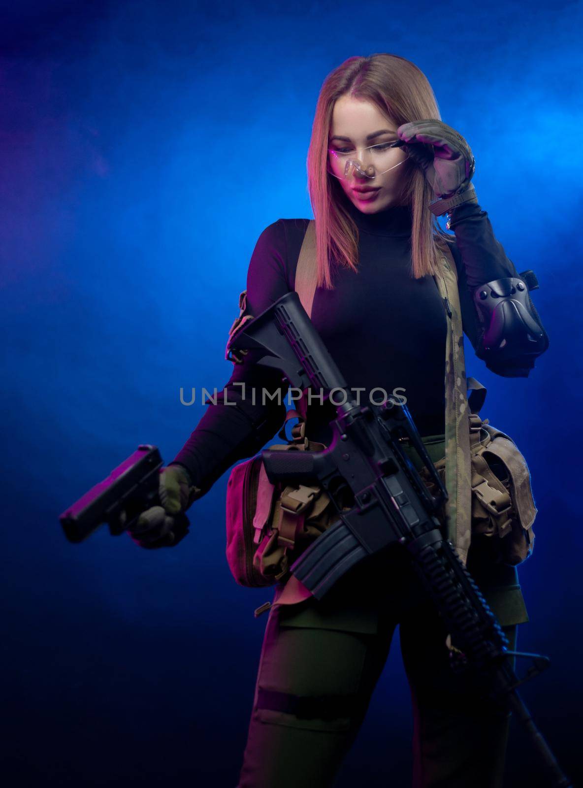 a woman in military airsoft uniform with an American automatic rifle and pistol on a dark background by Rotozey