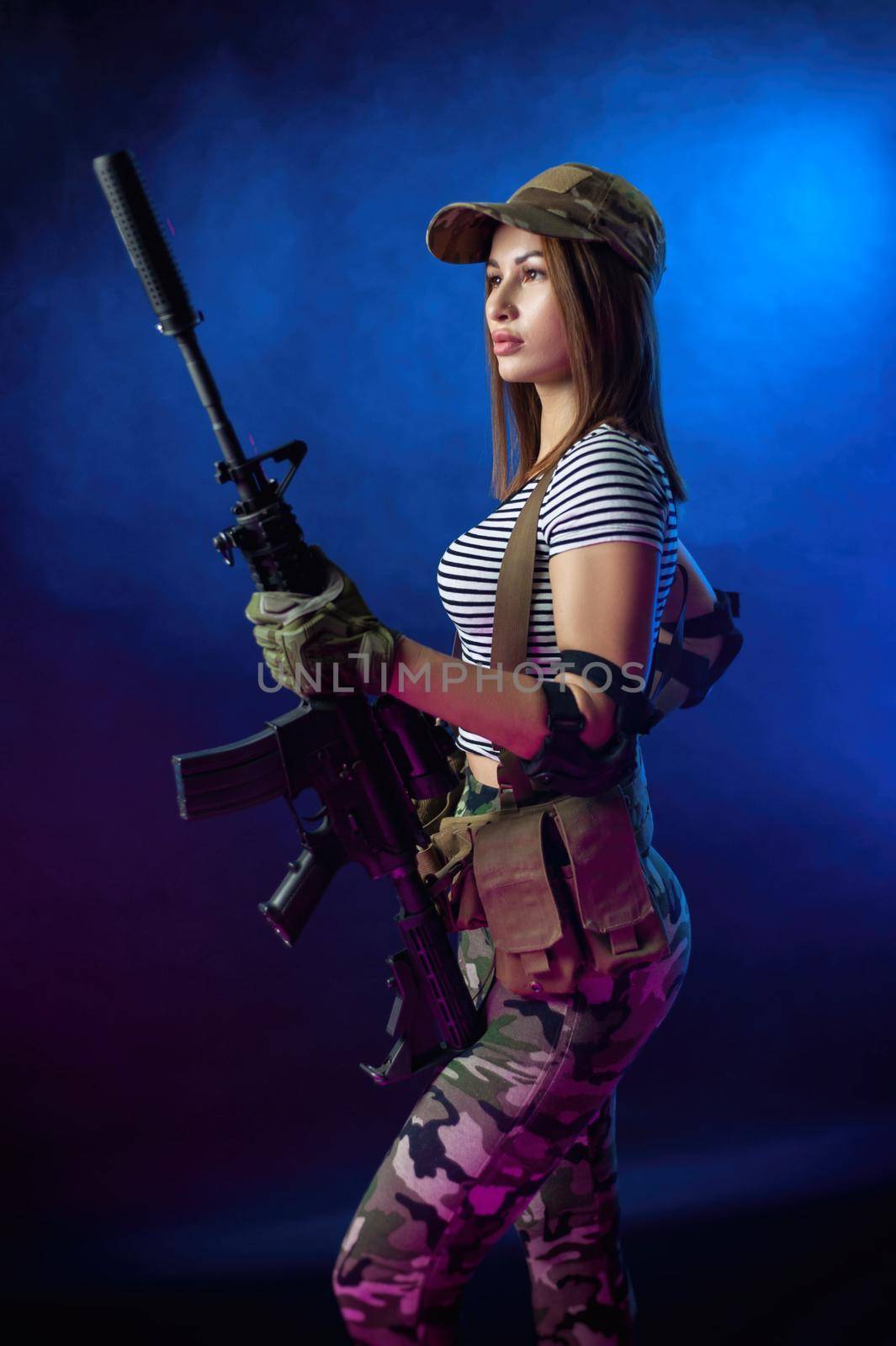 a woman in a military airsoft uniform in a vest with an American automatic rifle on a dark background by Rotozey