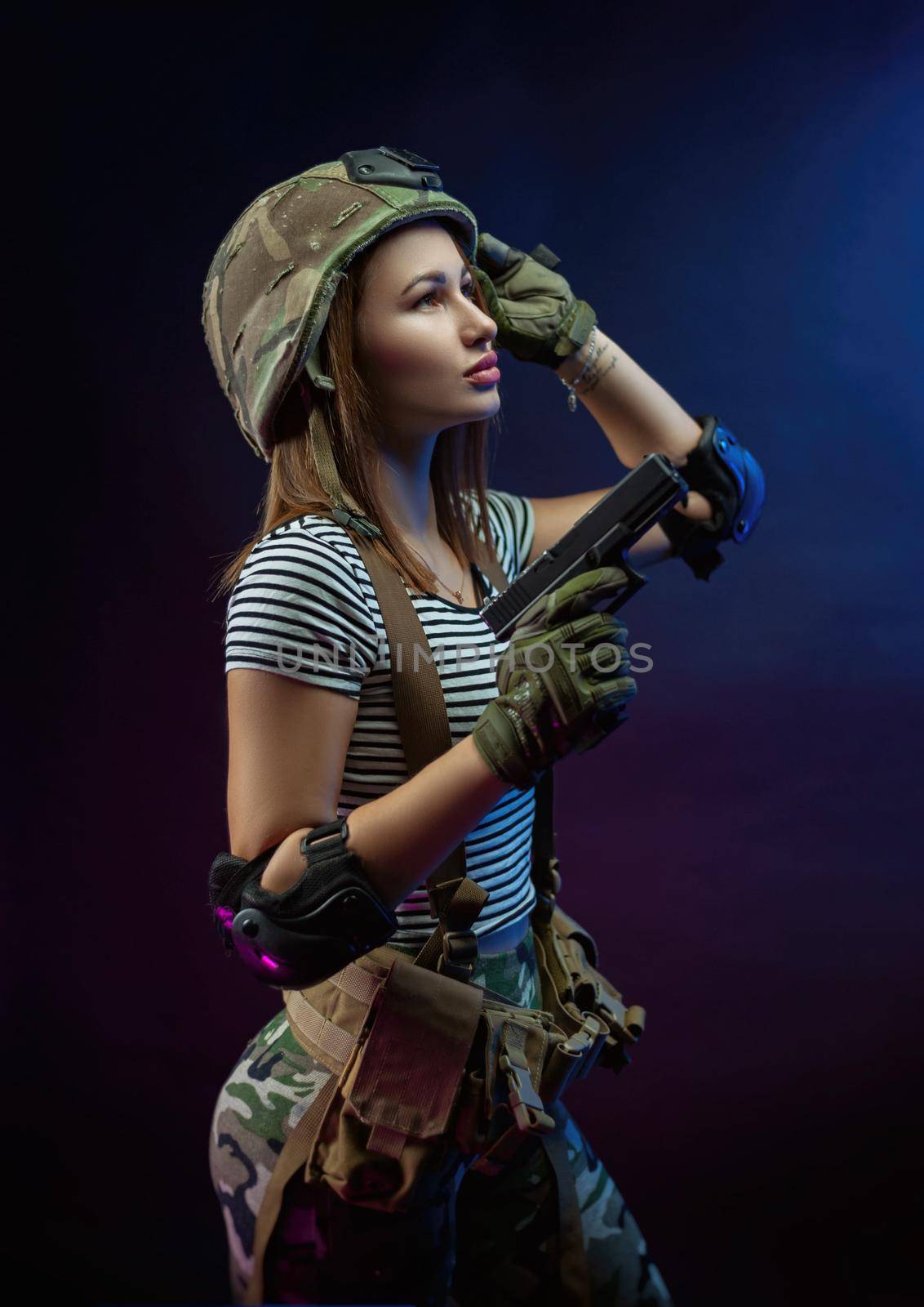 a woman in a military airsoft uniform with an American automatic rifle and a helmet on a dark background by Rotozey