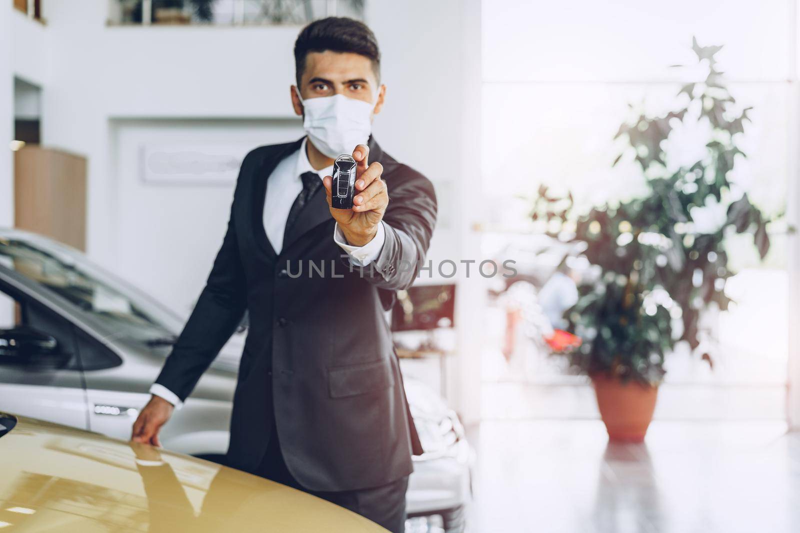 Man car dealer wearing protective medical mask on his working place, coronavirus prevention concept