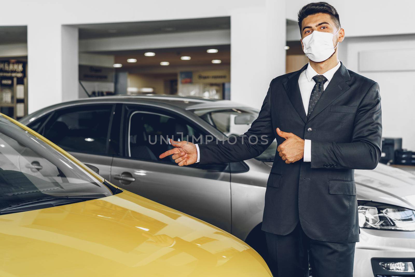 Man car dealer wearing protective medical mask on his working place, coronavirus prevention concept