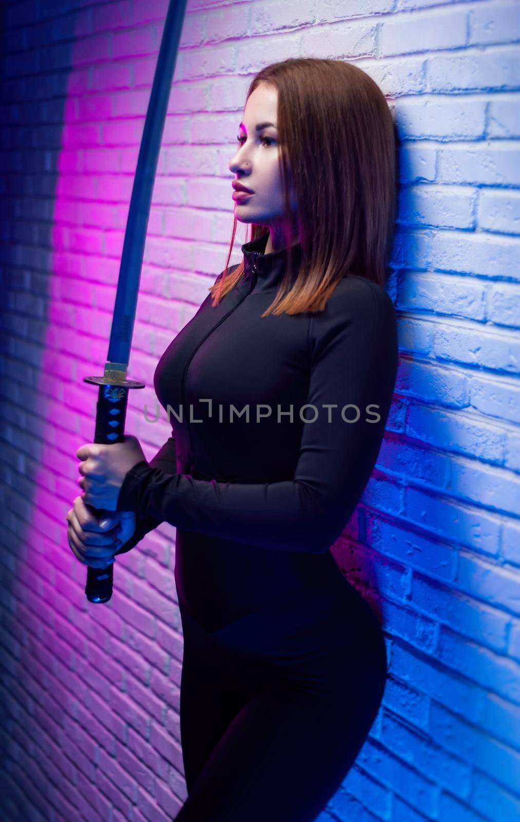 the sexy slender woman in black clothes with a katana in her hand in neon light