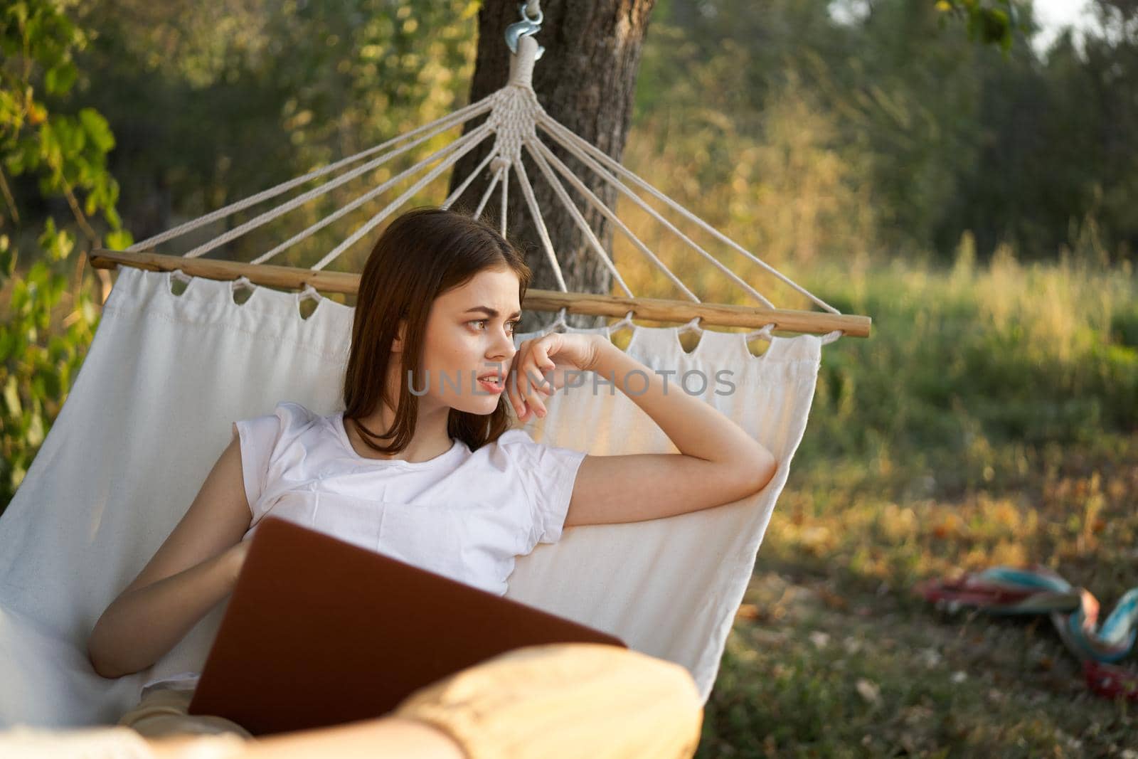 cheerful woman lies in a hammock with a laptop vacation internet travel. High quality photo