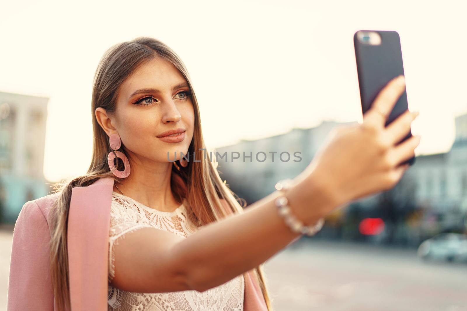 Young nice woman making selfie in the street. Close up.