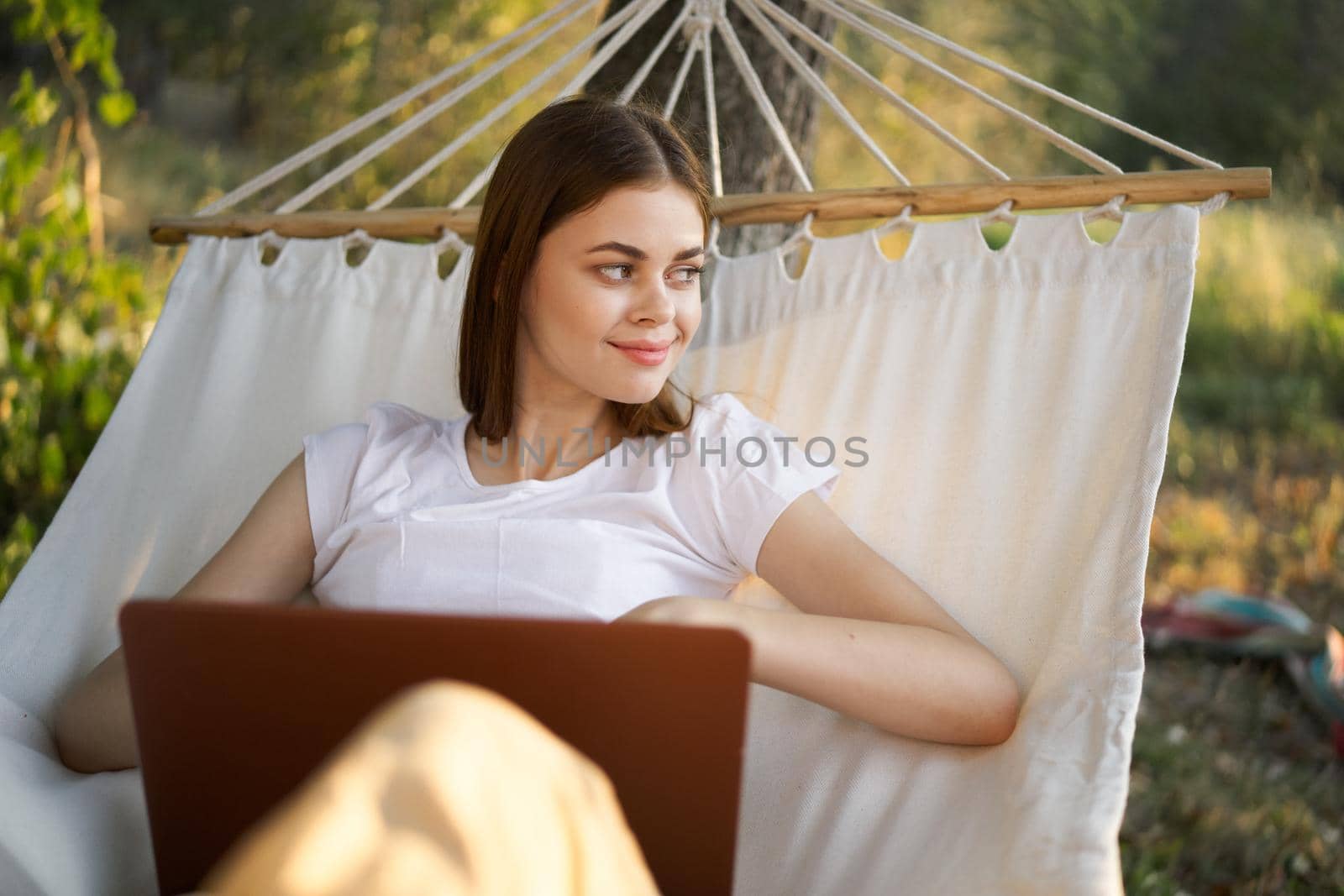 woman working in front of laptop in a hammock in nature. High quality photo