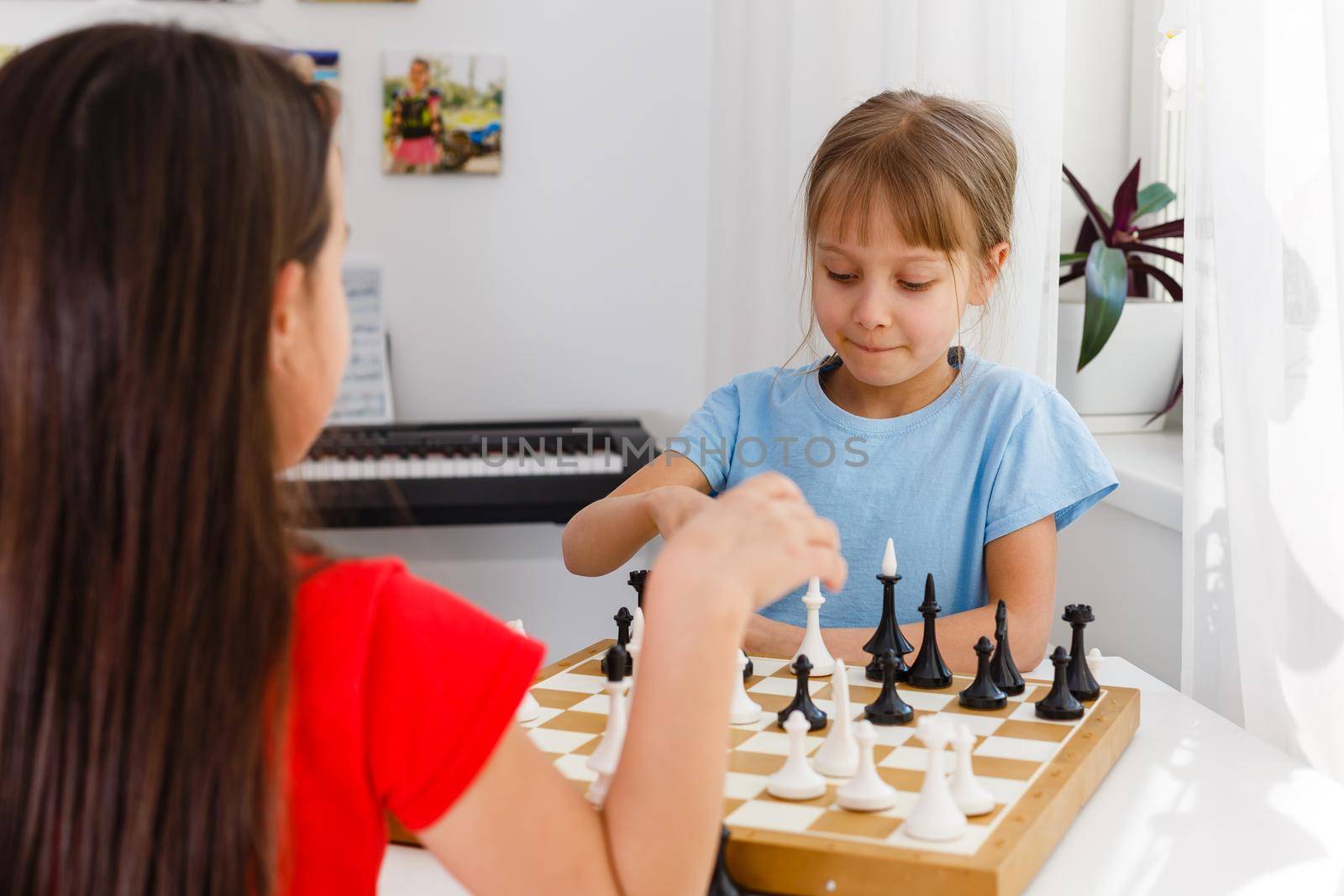 Two little sister playing chess at home by Andelov13