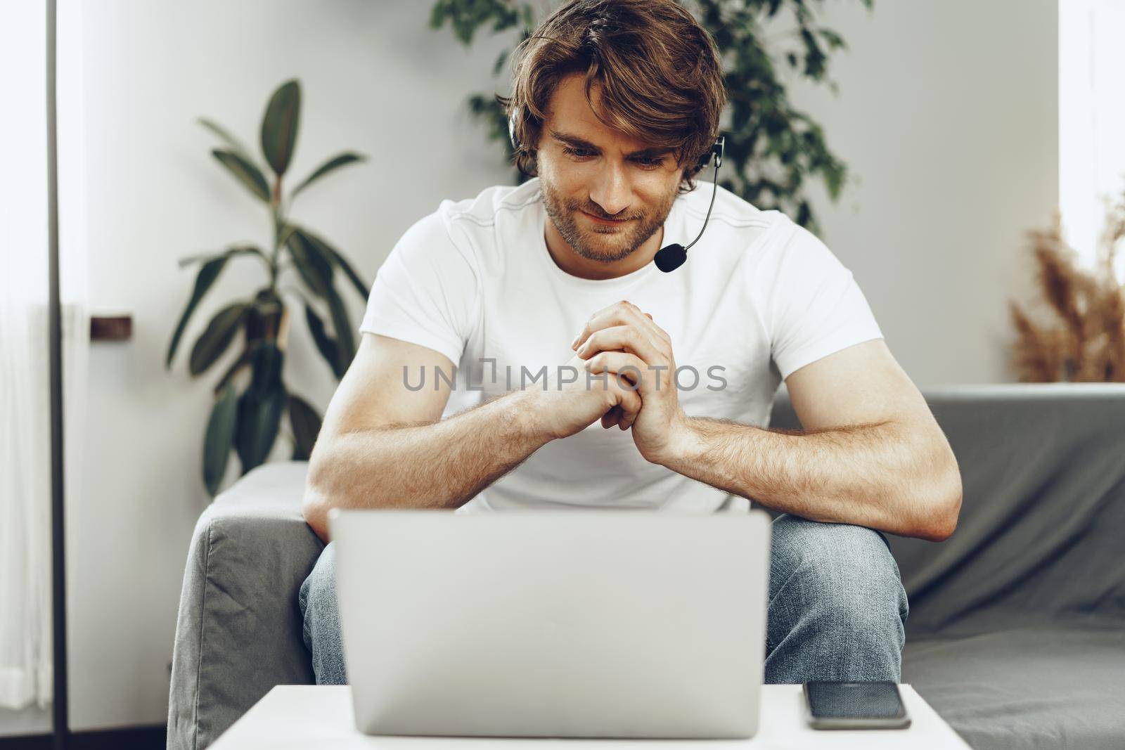 Young man businessman with headset working on laptop from home. Home office concept