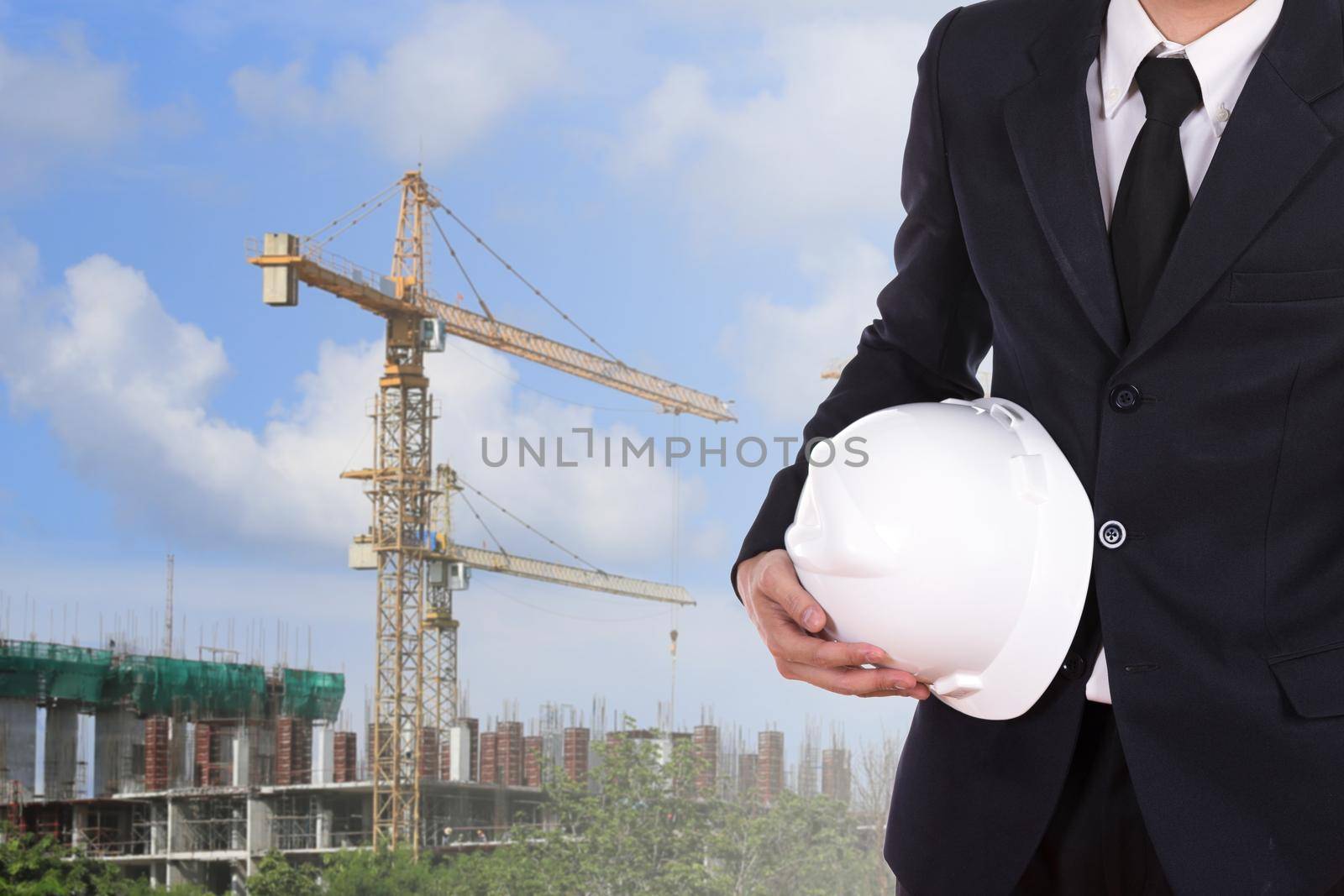 engineer holding helmet with construction crane background by geargodz