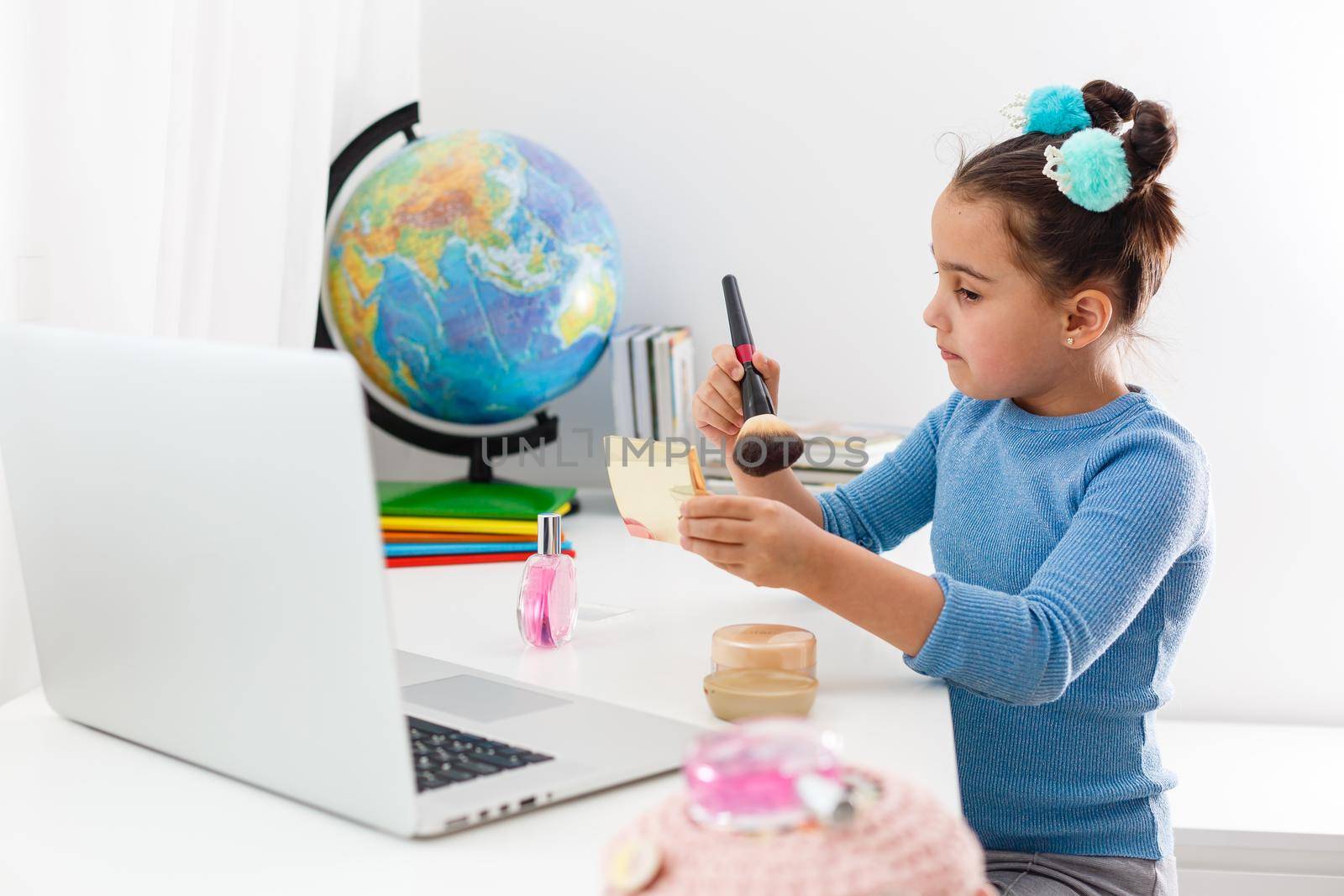 little girl learning make up powder, brush, blush on laptop online, distance learning