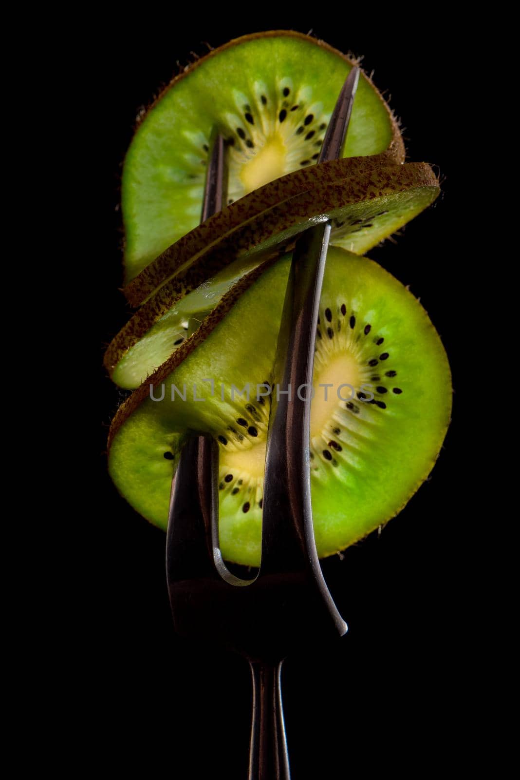 Sliced fresh and juicy green kiwi on the silver fork on dark background. healthy food concept. close up. low key. 5