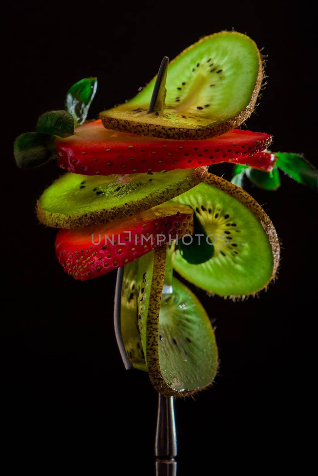 Sliced fresh and juicy green kiwi and red strawberry on the silver fork on dark background. healthy food concept. close up. low key.6