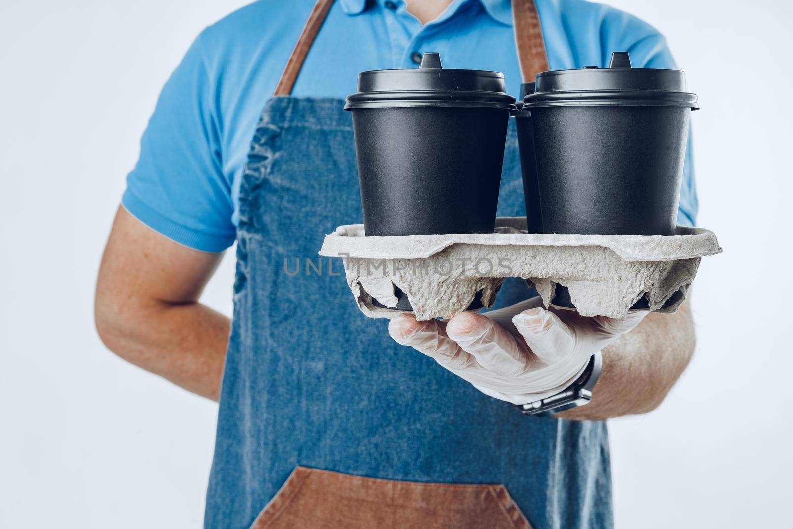 Man coffee shop worker giving takeaway cups of coffee on light grey background