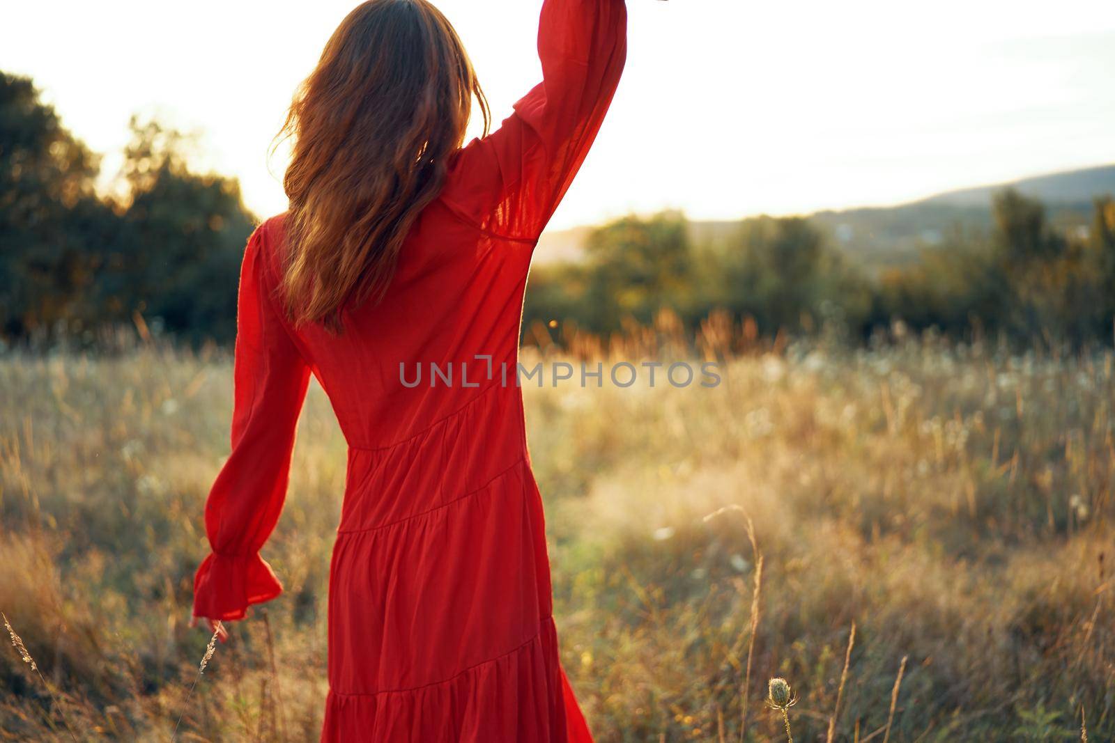 woman in red dress in the field walk freedom landscape. High quality photo