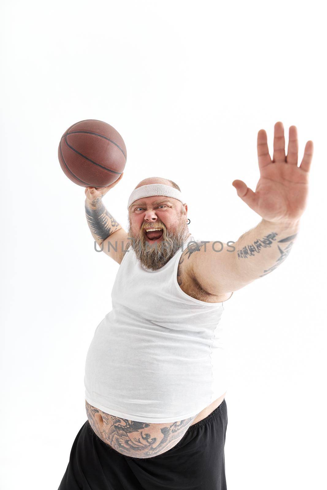 bearded fat caucasian tattoed man with basketball ball in white background. He is funny and happy by Yaroslav_astakhov