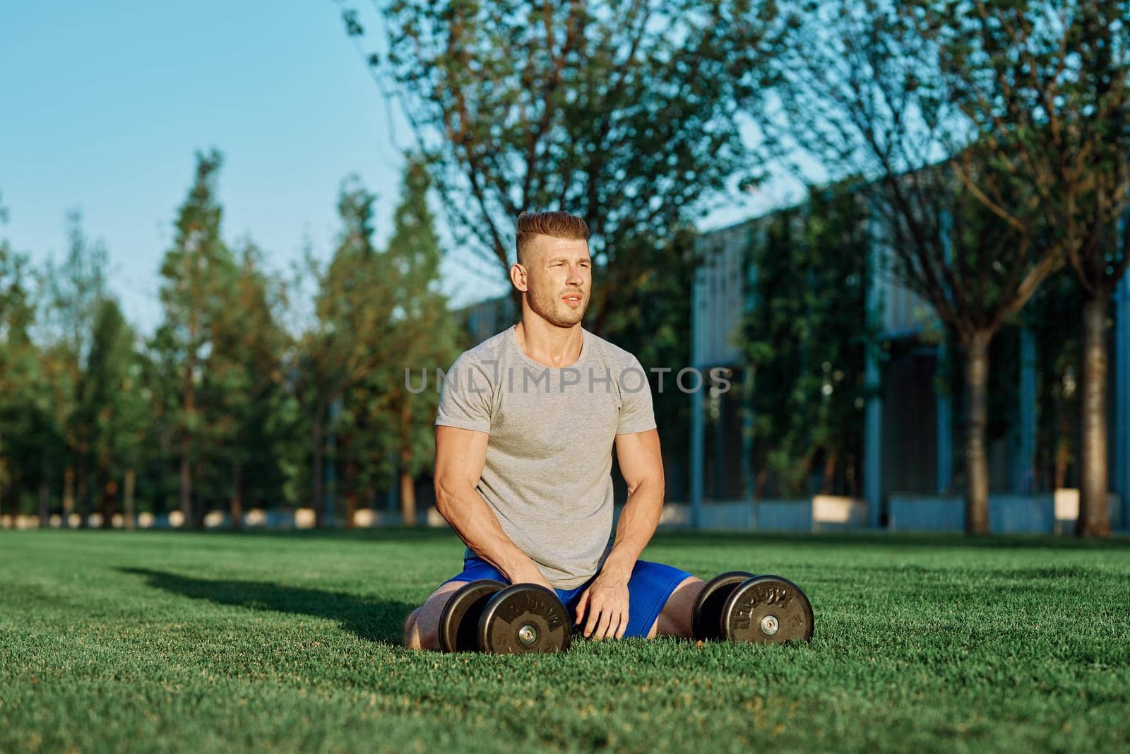 athletic man with dumbbells in the park exercise motivation. High quality photo