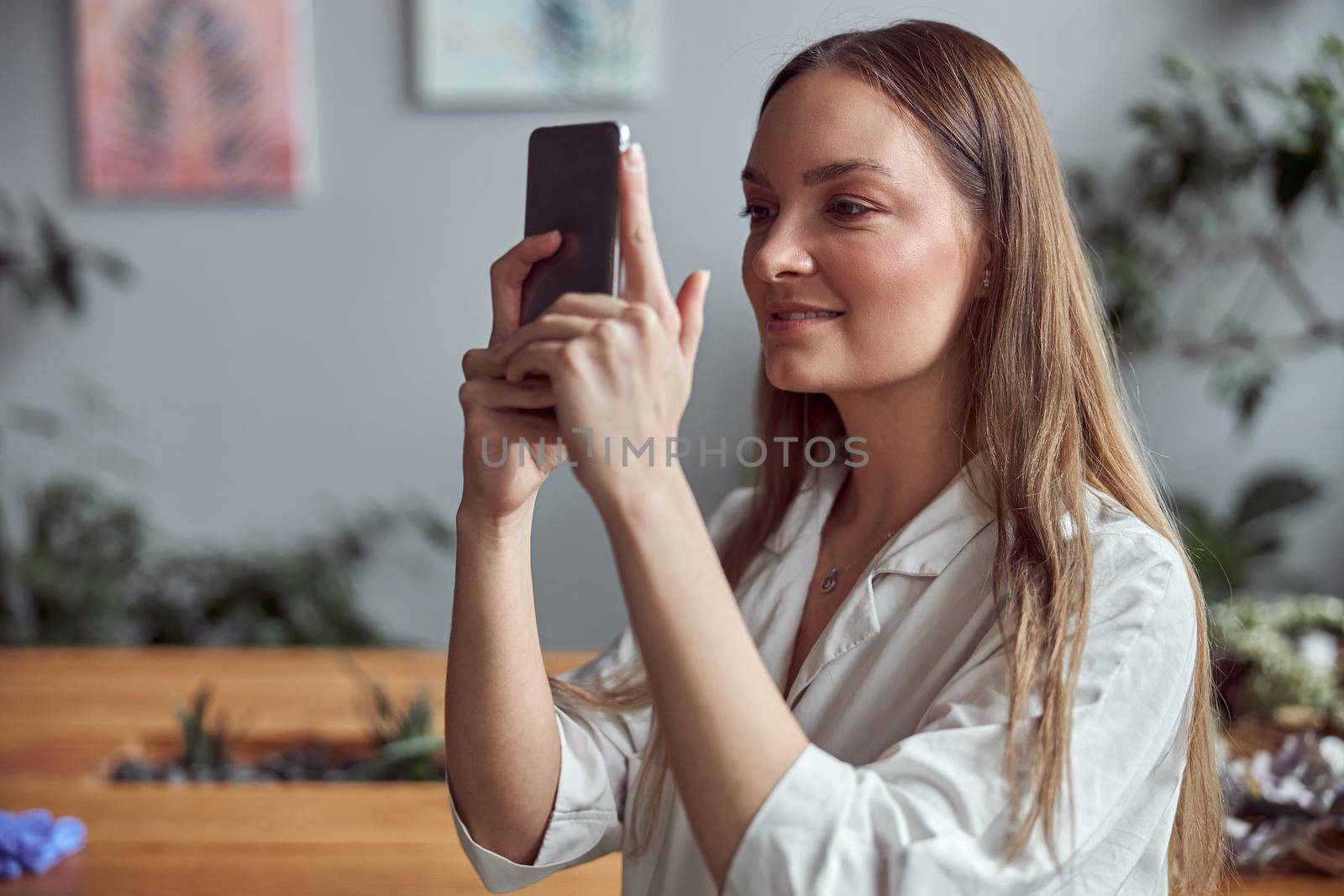 Confident female woman is taking photo on her smartphone