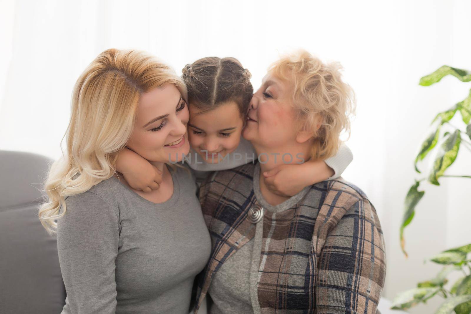 Portrait of three generations of women look at camera posing for family picture, cute little girl hug mom and granny enjoy time at home, smiling mother, daughter and grandmother spend weekend together