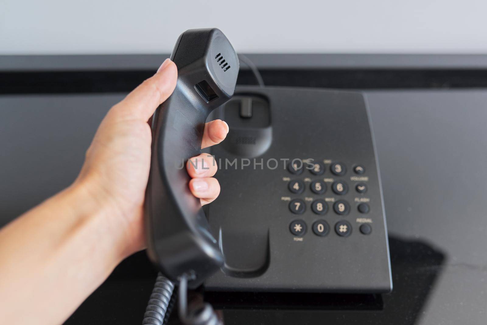 Telephone in a hotel room, hand with a raised telephone receiver close-up. Service, help, maintenance, communication with the administration reception