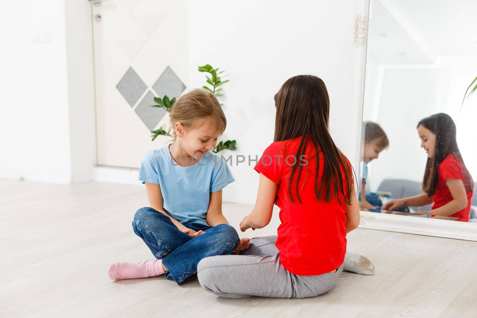 two little girls play with a hamster on the floor at home