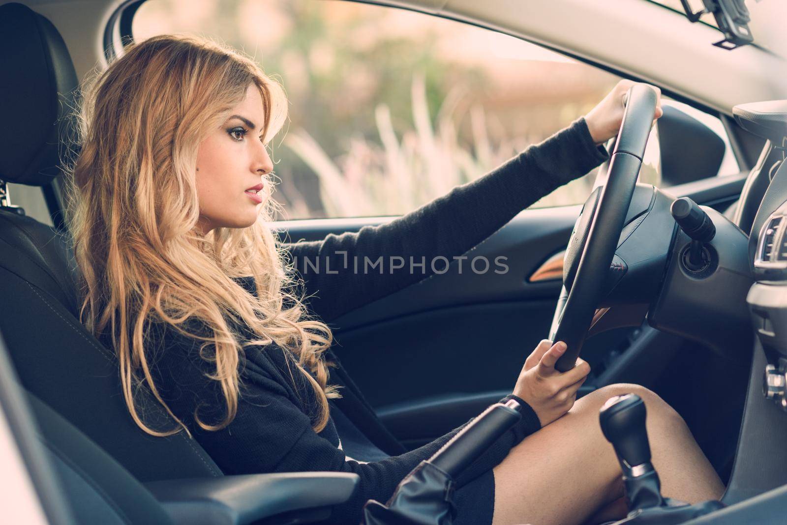 Blondie young girl driving a sport car looking at the road